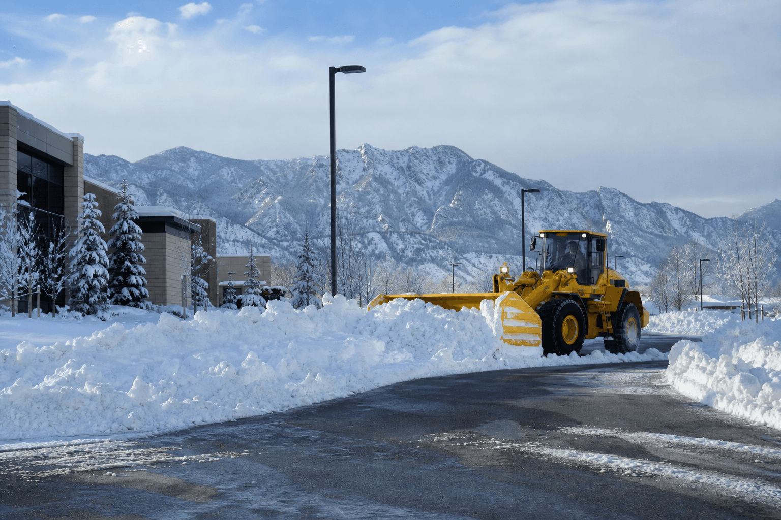 Heavy equipment clearing snow from a Colorado lot